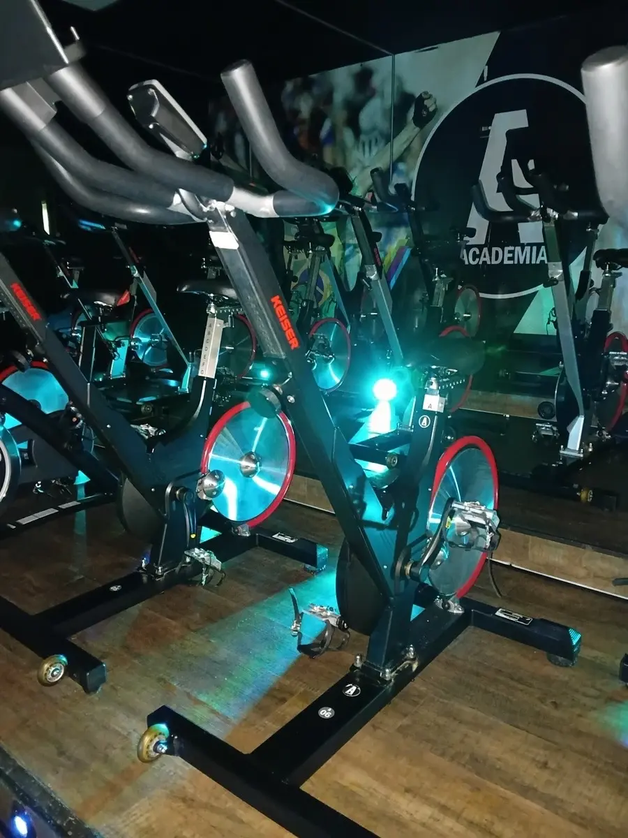 Sala de spinning com bicicletas e iluminação cênica